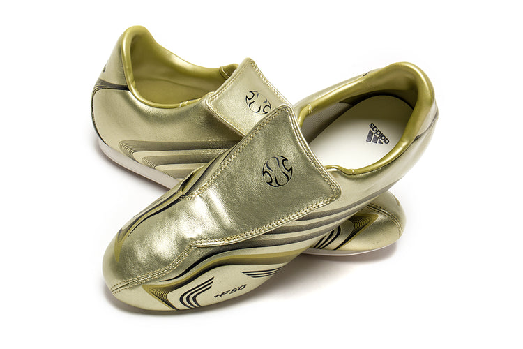 Adidas - Women's Taekwondo F50
Style # IH1872
Color : Gold Metallic / Core Black / Off White
Materials : Leather Upper - Rubber Outsole
Sizing : US Women's